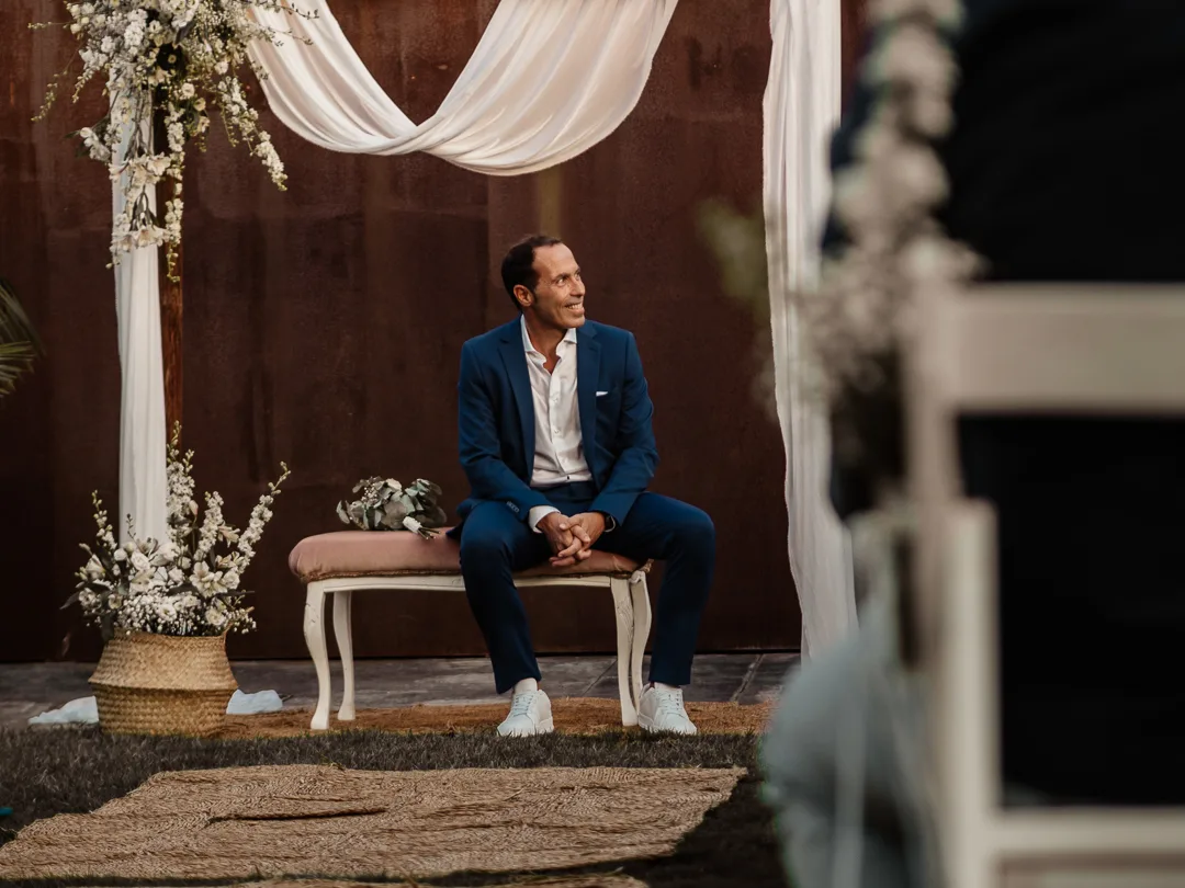 El nuvi somrient assegut sota l'altar decorat